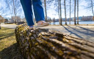 Kuvassa henkilö kävelee puunrungolla.