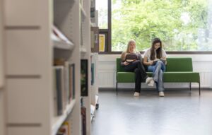 Nuoret istuvat kirjaston penkillä ja lukevat