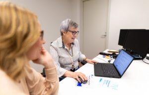 Asiakaspalvelija näyttää asiakkaalle jotain läppäriltä
